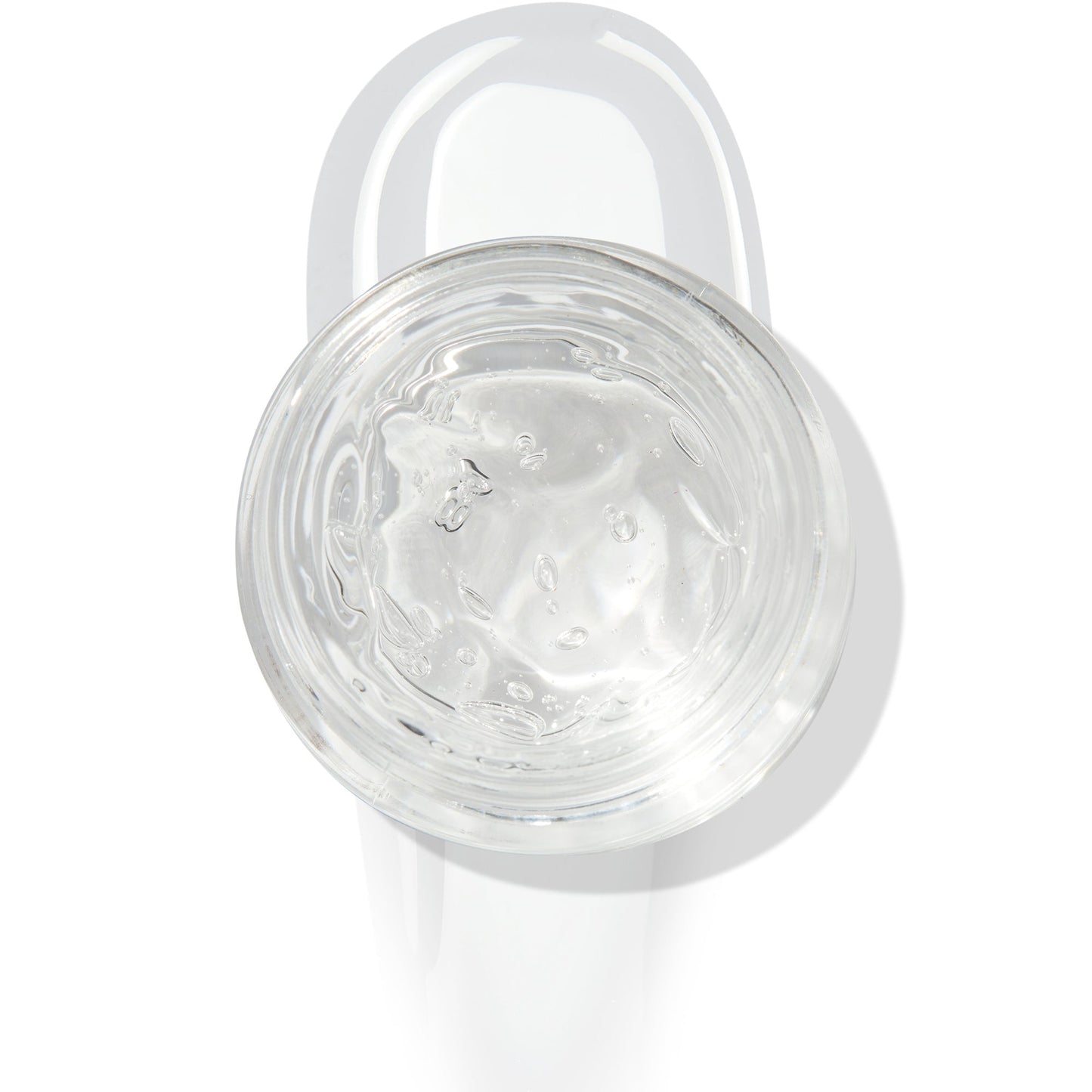 In The Clear Face & Eye Gloss in an open round jar gleams with a glossy swipe beneath it on a white background, showcasing the ColourPop Face & Eye Gloss for dewy, glass-skin shine on lids and cheeks.