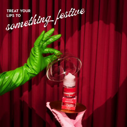 Green-gloved hand holding a lip balm against a red curtain with text 'Treat your lips to something festive'.