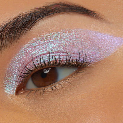 Close-up of an eye wearing Colourpop Disco Disco Shadow Stix, showing a bold wing of iridescent pink-lilac shimmer blended across the lid and crease against smooth warm-toned skin, highlighting the creamy metallic eyeshadow finish.